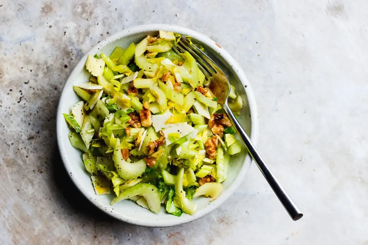 Frischer Staudensellerie Salat italienisch mit Walnüssen und Parmesan, serviert in einer Schüssel mit einer Gabel.