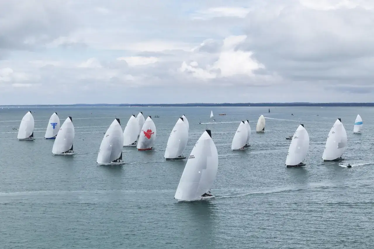 Segelboote k&auml;mpfen um die Admirals Cup Troph&auml;e. Wei&szlig;e Segel dominieren das Bild, w&auml;hrend die Boote &uuml;ber das Meer gleiten.