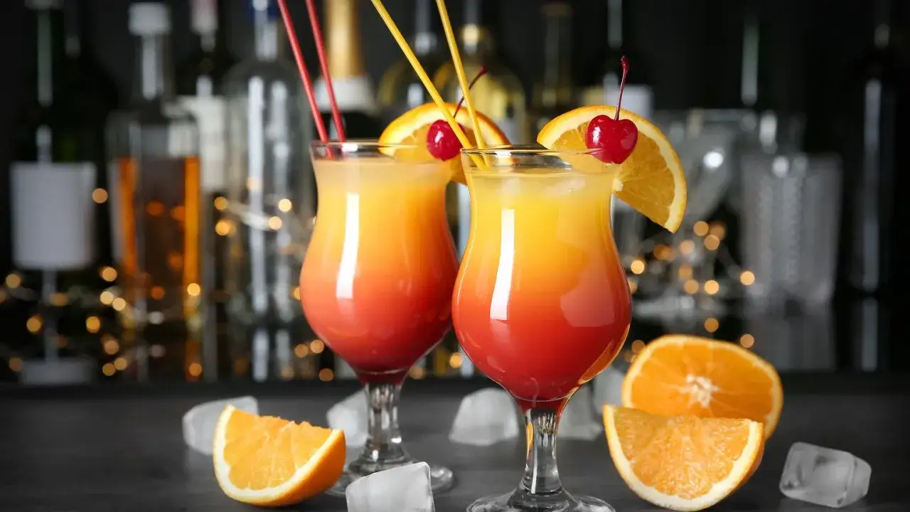 Dwa orzeźwiające drinki z wódką, udekorowane pomarańczą i wiśnią, stoją na barze.
