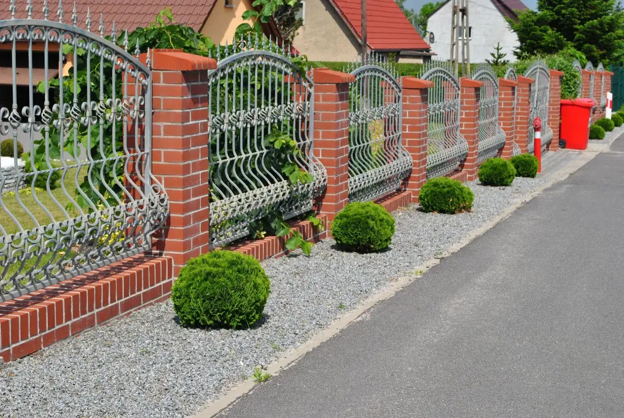 Eleganckie ogrodzenie z cegły i metaloplastyki, idealne jako wzór umowy z sąsiadem na ogrodzenie.