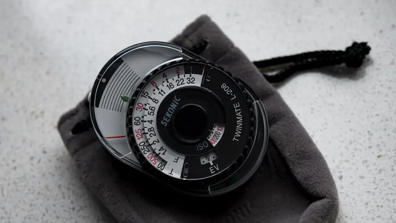 Stary, analogowy światłomierz Sekonic Twinmate L-208 leży na szarym etui.