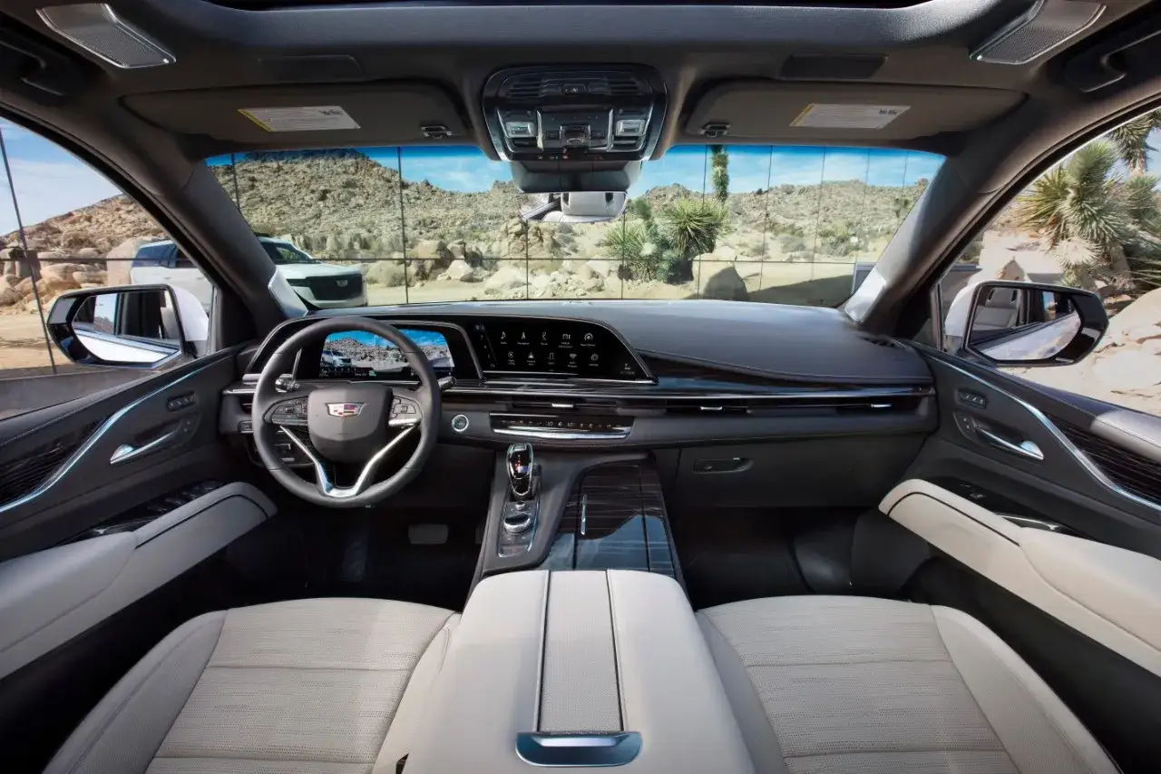 Wnętrze Cadillac Escalade 2025 z nowoczesnym panelem, ekranami i jasnymi skórzanymi fotelami.