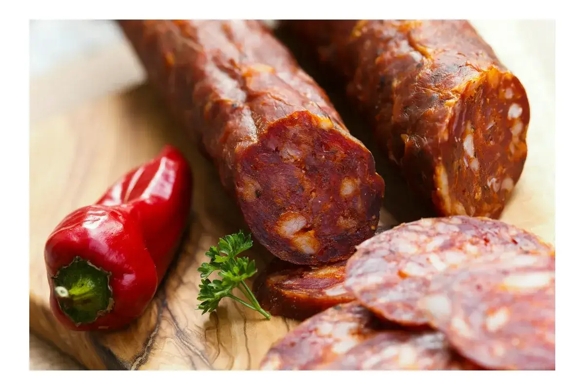 Chorizo co to? Pikantna kiełbasa, czerwona papryka i natka pietruszki na desce.