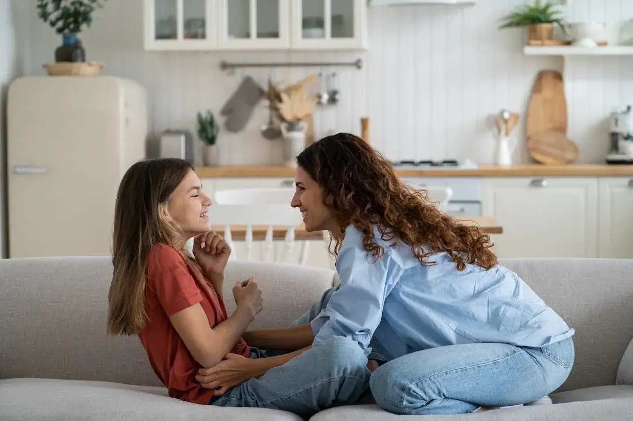 Madre habla con su hija en el sof&aacute;. Le explica que la menstruaci&oacute;n a los 10 a&ntilde;os es normal y parte de crecer.