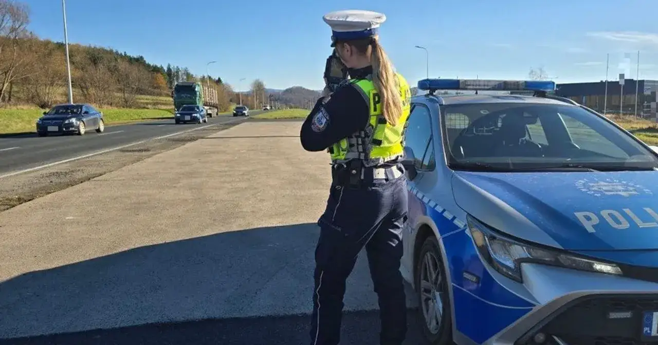 Policjantka mierzy prędkość pojazdów, przypominając o taryfikatorze mandatów za prędkość.