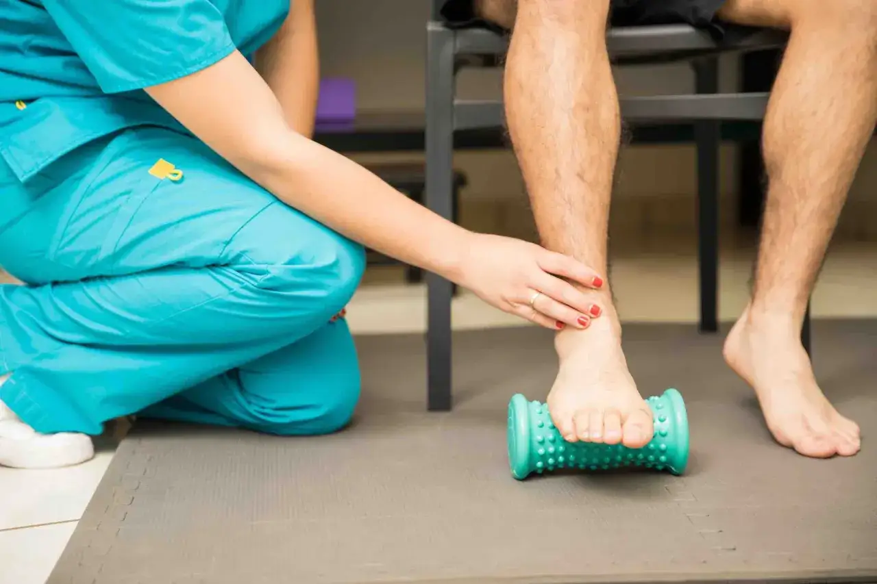 Fisioterapeuta ayuda a paciente a aliviar dolor con rodillo para fascitis plantar. Descubre c&oacute;mo eliminar la fascitis plantar en 72 horas.