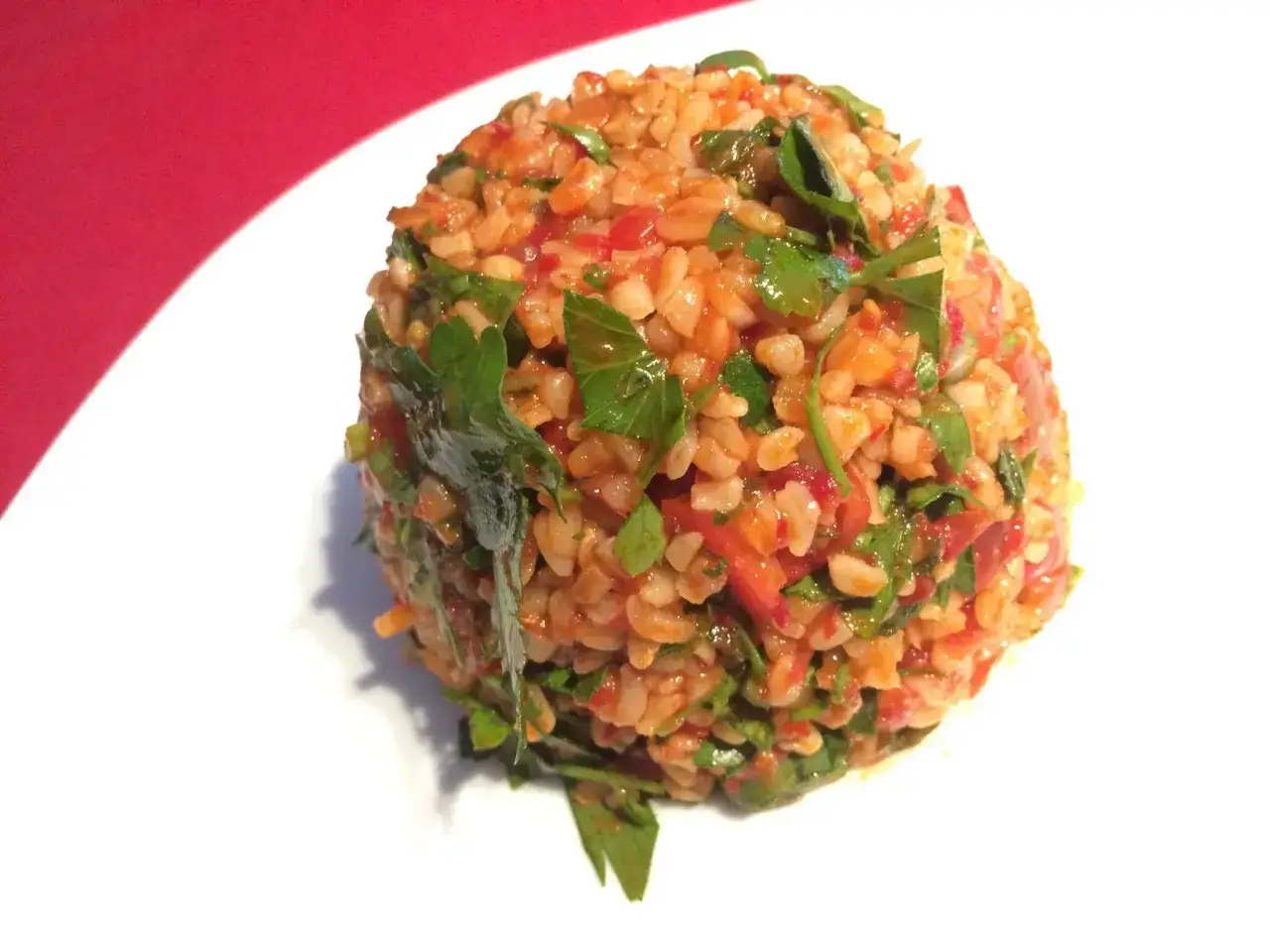 Ein appetitlicher Bulgursalat, der aussieht wie das beste bulgursalat rezept, mit frischer Petersilie und Tomaten auf einem wei&szlig;en Teller.