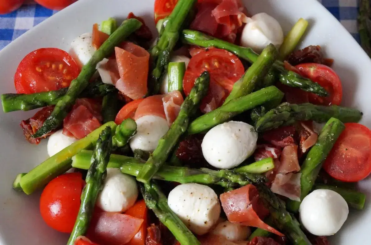 Pyszna sałatka ze szparagami, pomidorkami, mozzarellą i szynką parmeńską.