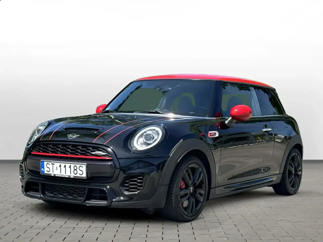 Czarny Mini Cooper z czerwonym dachem i lusterkami. Wiele osób chwali ten model, a jego opinie są bardzo pozytywne.