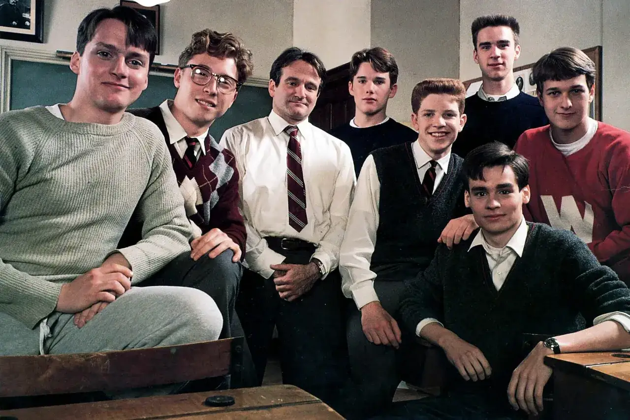 Stowarzyszenie Umarłych Poetów obsada: Robin Williams i młodzi aktorzy w szkolnych strojach.