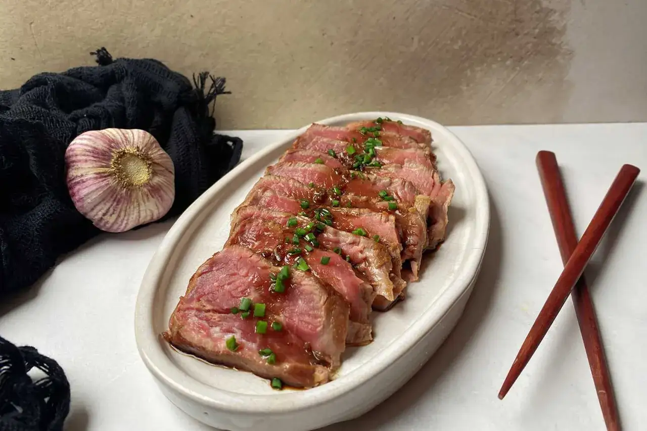 Tataki de ternera jugoso, cortado en finas lonchas y bañado en salsa. Acompañado de ajo y palillos.