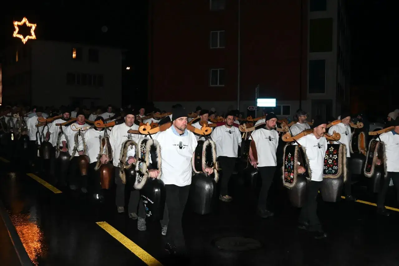 M&auml;nner mit grossen Glocken, die an Holzgestellen &uuml;ber den Schultern getragen werden, ziehen durch eine Schweizer Stadt. Ein festlicher Umzug, der an den Nikolaus erinnert.