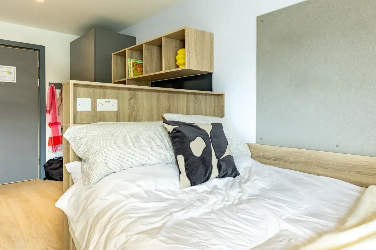 Chambre d'étudiant moderne à Cork, avec un lit confortable, des étagères et une porte.