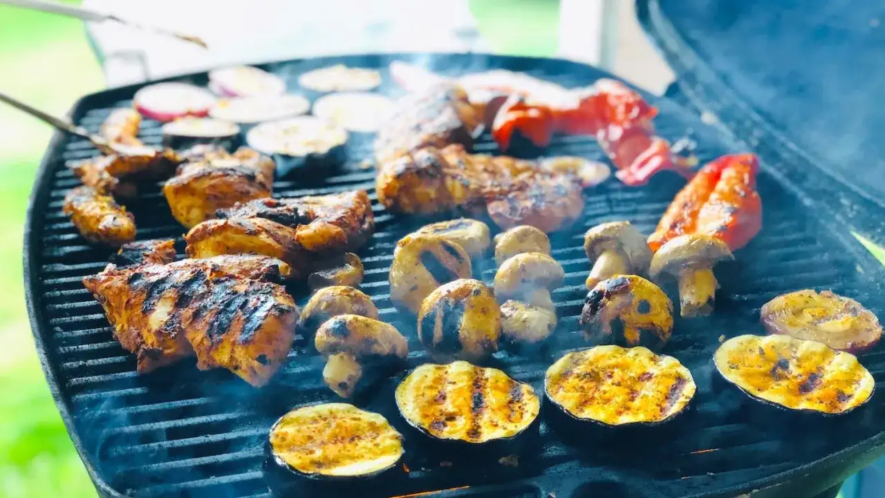 Kött, svamp och aubergineskivor grillas med en härlig egen marinad. Röken stiger från grillen.