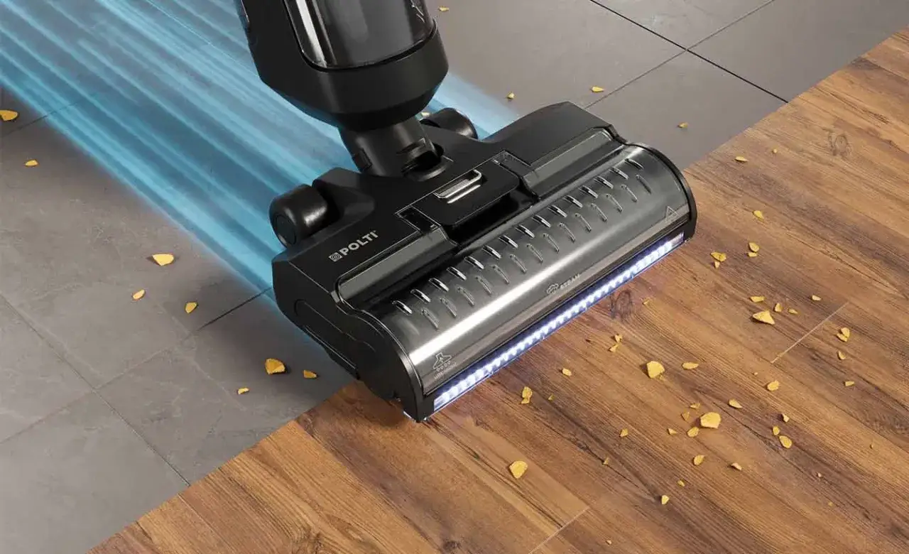 Un aspirapolvere Polti con luce LED pulisce un pavimento in legno e piastrelle, mostrando come lavare il pavimento in modo efficiente.