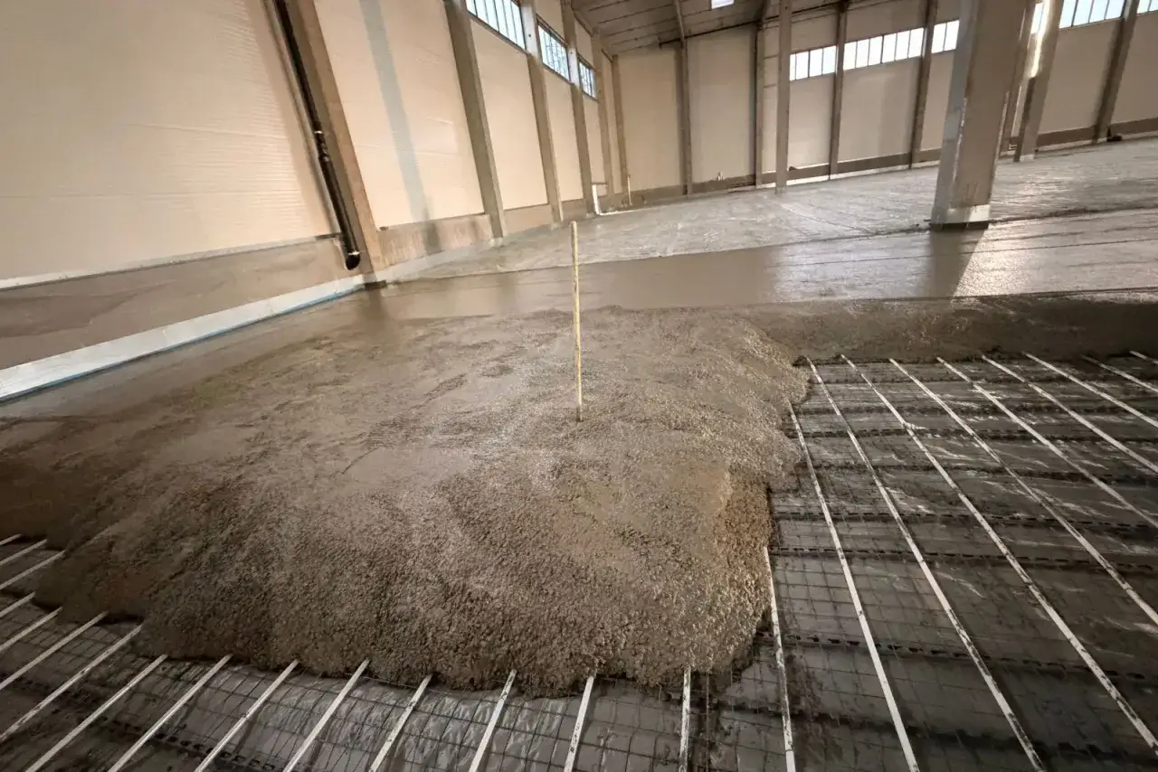 Frisch gegossener Beton C30/37 flie&szlig;t &uuml;ber eine Bewehrung in einer gro&szlig;en Halle.