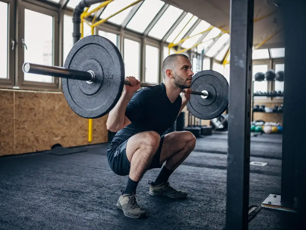 Man utför en rysk knäböj med skivstång i ett gym.