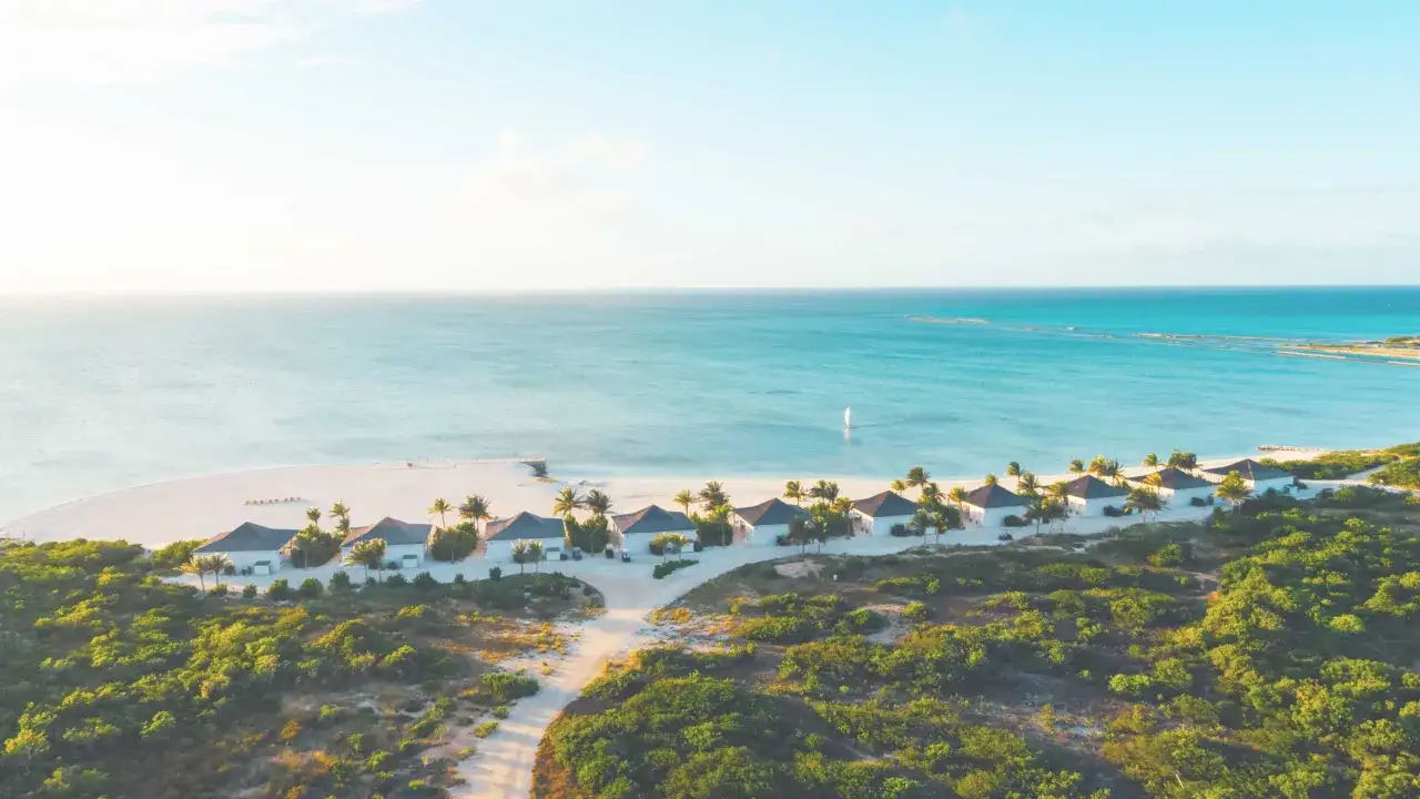 Traumhafte Bungalows am Strand des Club Marvy, mit Blick auf das türkisfarbene Meer und eine einsame Segelboot.