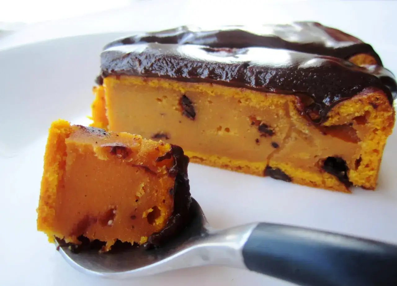 Deliciosa tarta de calabaza y chocolate, con trozos de chocolate incrustados y cubierta de ganache. Un bocado perfecto.