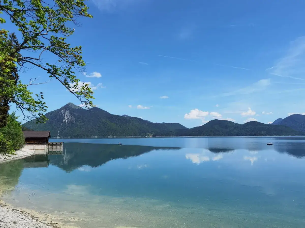 Karibik-Feeling am Walchensee: Ein Boot gleitet &uuml;ber das spiegelglatte Wasser, perfekt zum Baden und Entspannen.