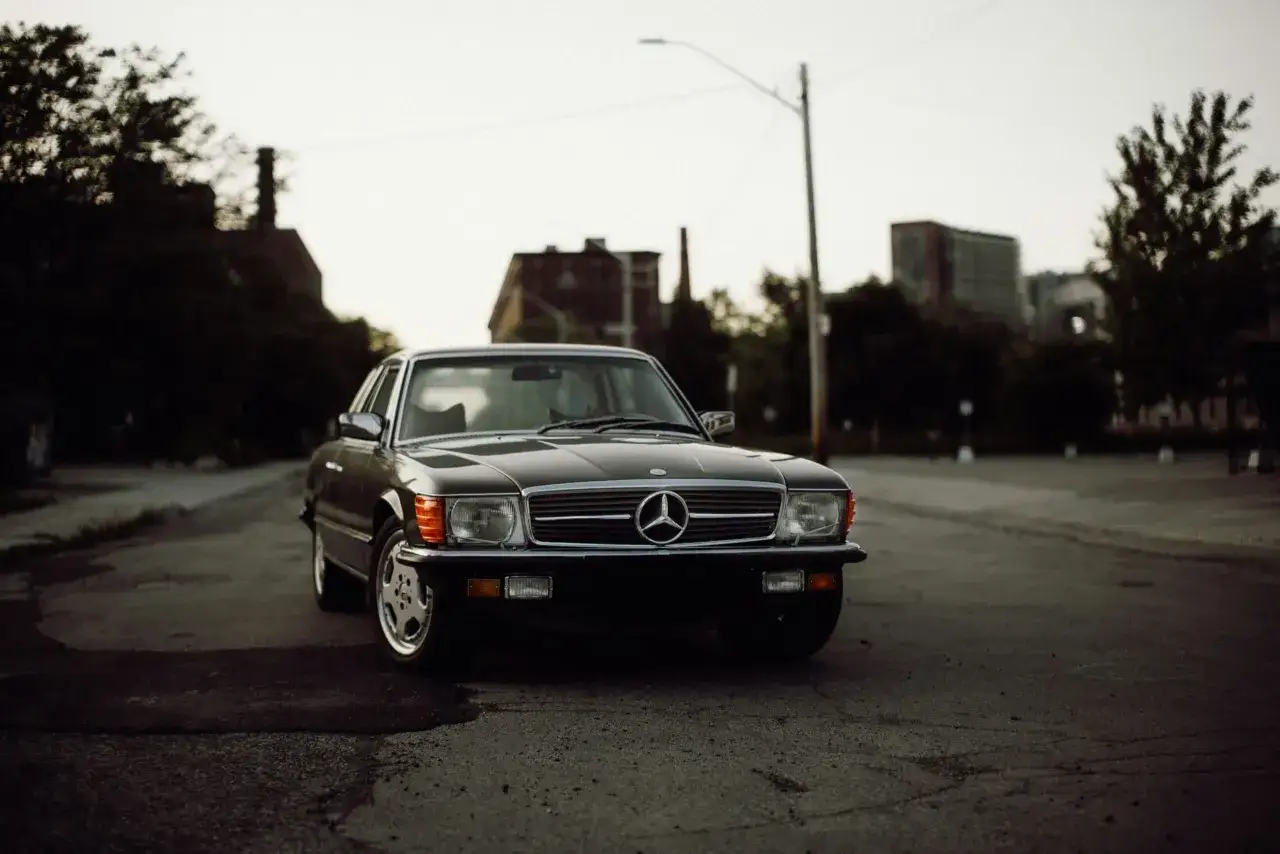 Klasyczny Mercedes SL na pustej drodze, z industrialnym krajobrazem w tle. To jakby chwila wytchnienia, break in classic, w miejskim zgiełku.