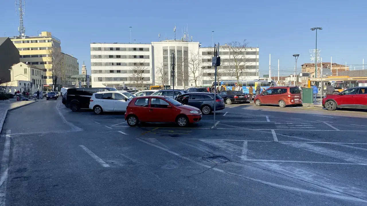 Parcheggio con auto e bus in Via Roma, Venezia. Una Fiat Punto rossa è in primo piano.