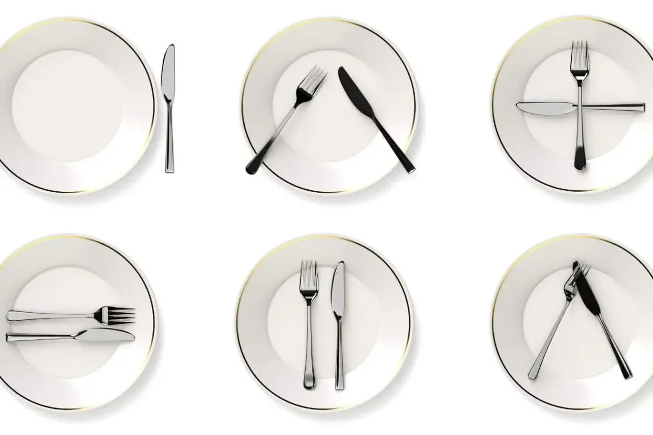 Six assiettes blanches avec des couverts disposés selon la position des couverts à la française, montrant différentes étapes d'un repas.