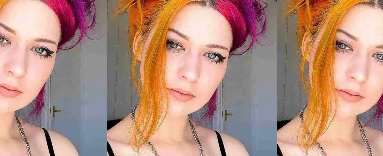 Ein Portr&auml;t einer jungen Frau mit auff&auml;lliger, zweifarbiger Haarfarbe: eine Seite leuchtend pink, die andere in einem warmen Orange-Gelb.