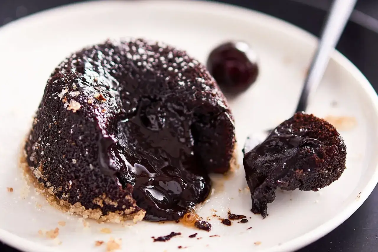 Tortino cuore caldo, la ricetta infallibile per un dessert al cioccolato fondente che cola. Perfetto con una ciliegia.