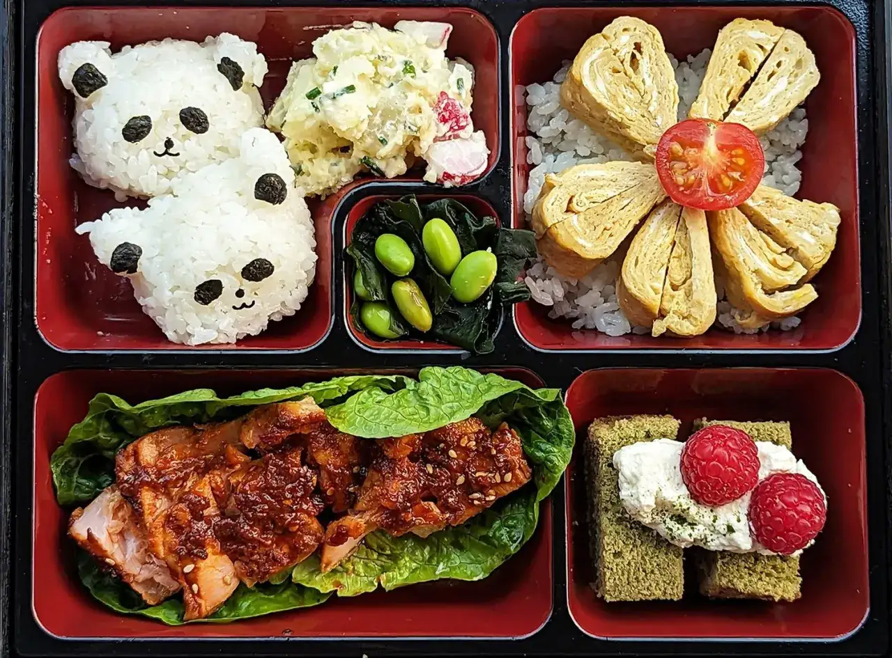 A cute panda bento box with rice pandas, potato salad, edamame, tamagoyaki, salmon, and matcha cake. This is what bento is all about!
