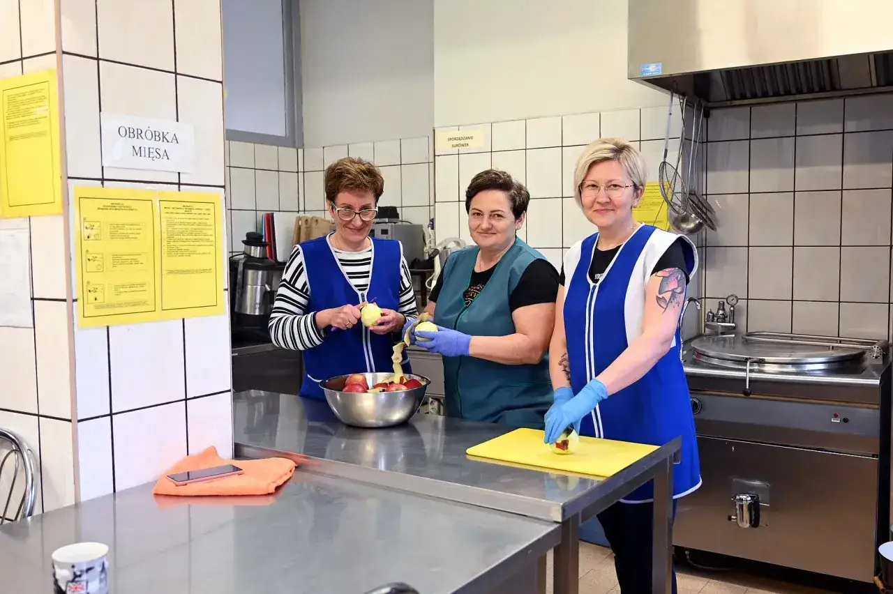 Trzy pracownice kuchni, w tym intendentka, obierają jabłka.