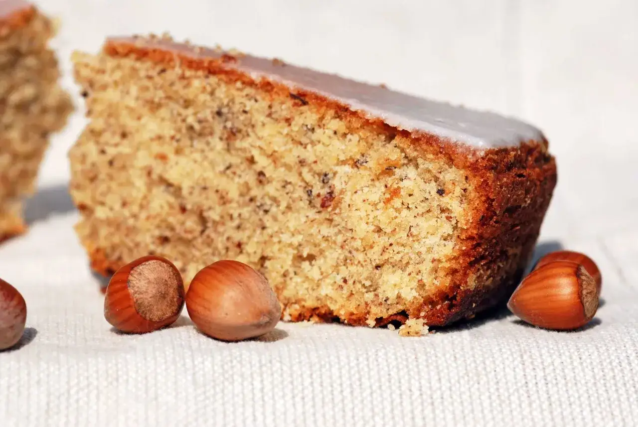 Une part de g&acirc;teau moelleux aux noisettes de ma mamie, avec quelques noisettes enti&egrave;res pos&eacute;es &agrave; c&ocirc;t&eacute;.