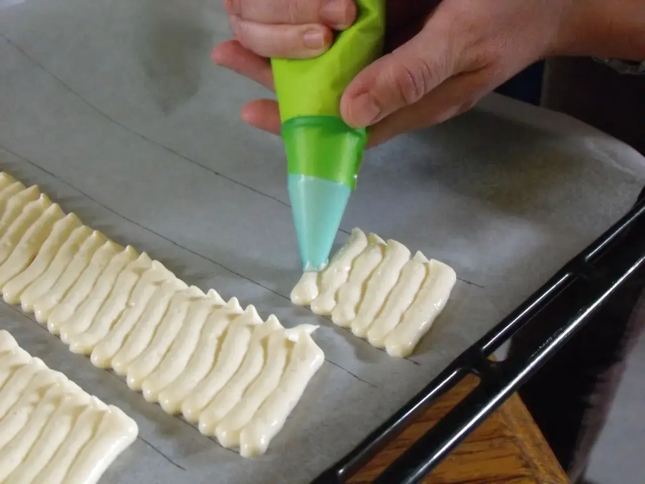 Préparation d'un délicieux gâteau à la cuillère, la pâte est dressée à la poche à douille sur une plaque de cuisson.