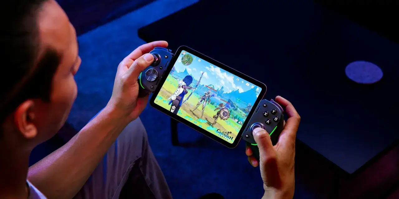 Gracz z kontrolerami w dłoniach zanurza się w świecie gry na iPadzie. Wciągające gry na ipada zapewniają rozrywkę.