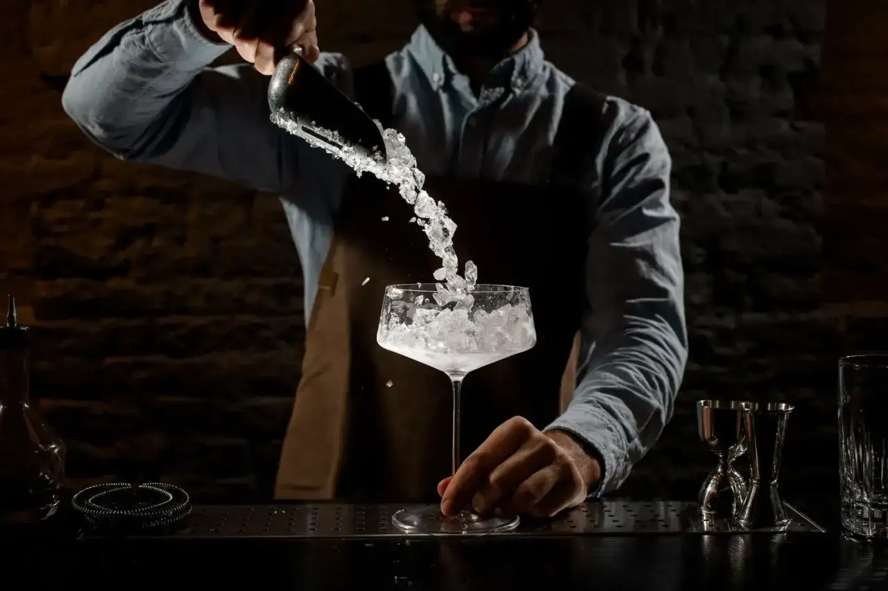 Barman versa ghiaccio per cocktail che non si scioglie in un bicchiere.