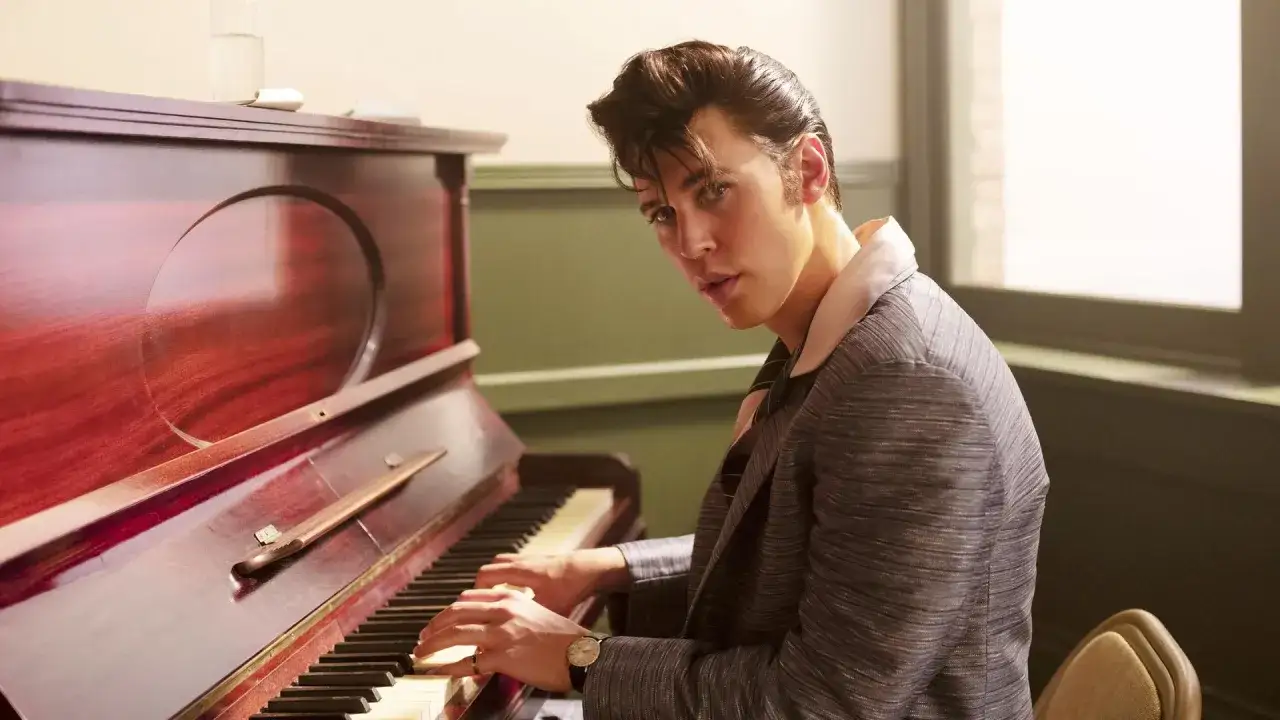 Austin Butler als Elvis Presley im Film, der am Klavier sitzt und in die Kamera blickt.
