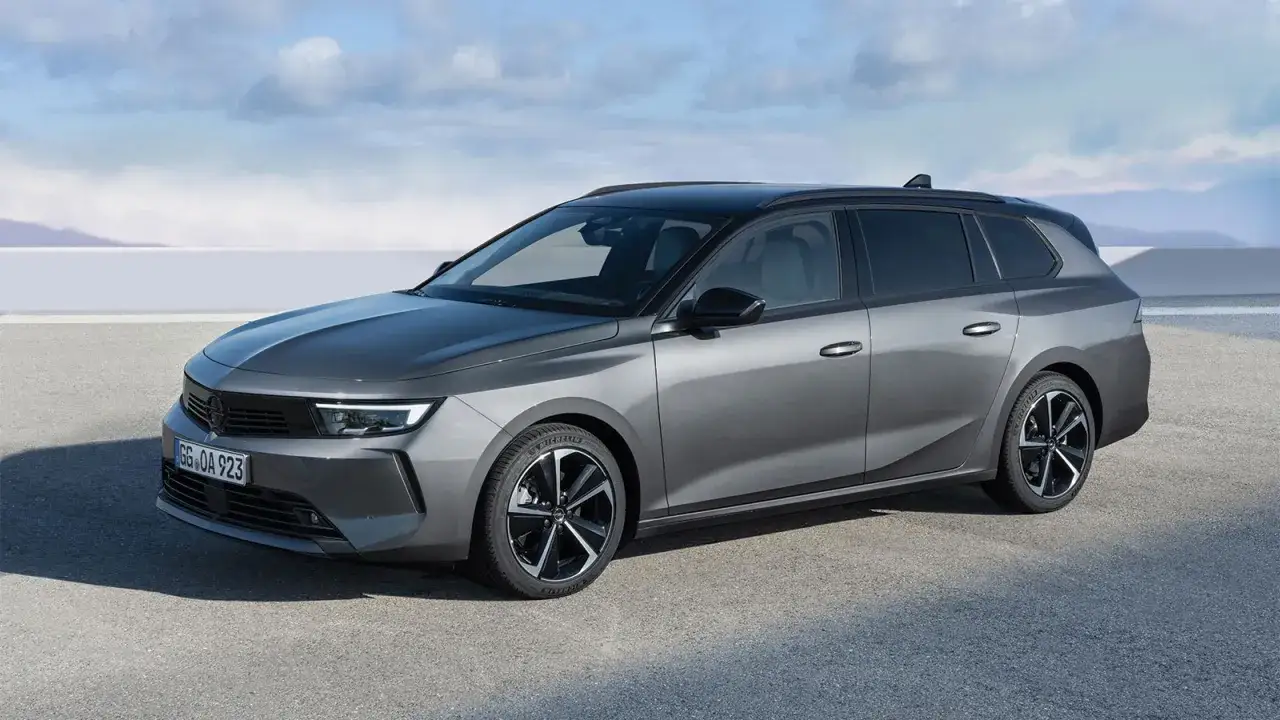 Szary Opel Astra 2025 kombi z czarnym dachem, zaparkowany na zewnątrz.