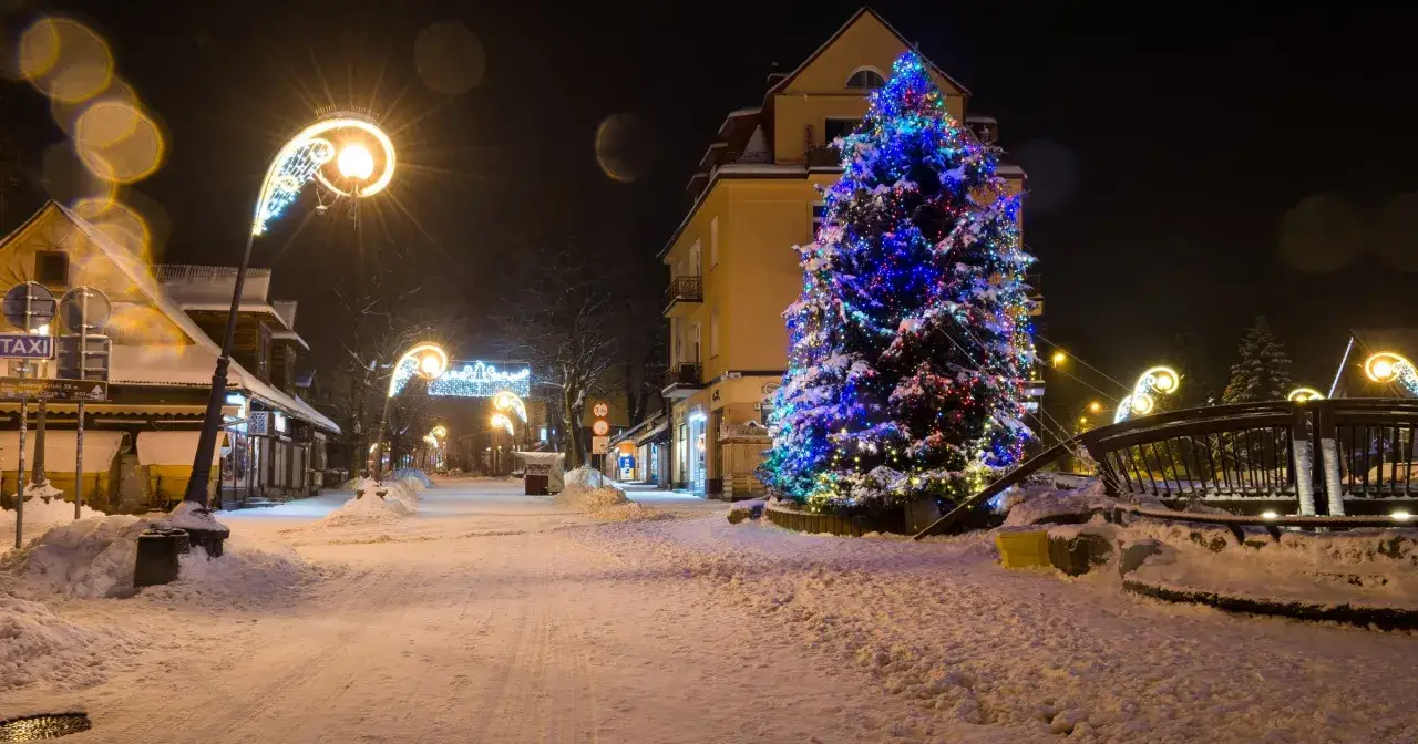 Śnieżna noc w Zakopanem, rozświetlona choinka i latarnie. Zastanawiasz się, ile kosztuje nocleg w zakopanem?