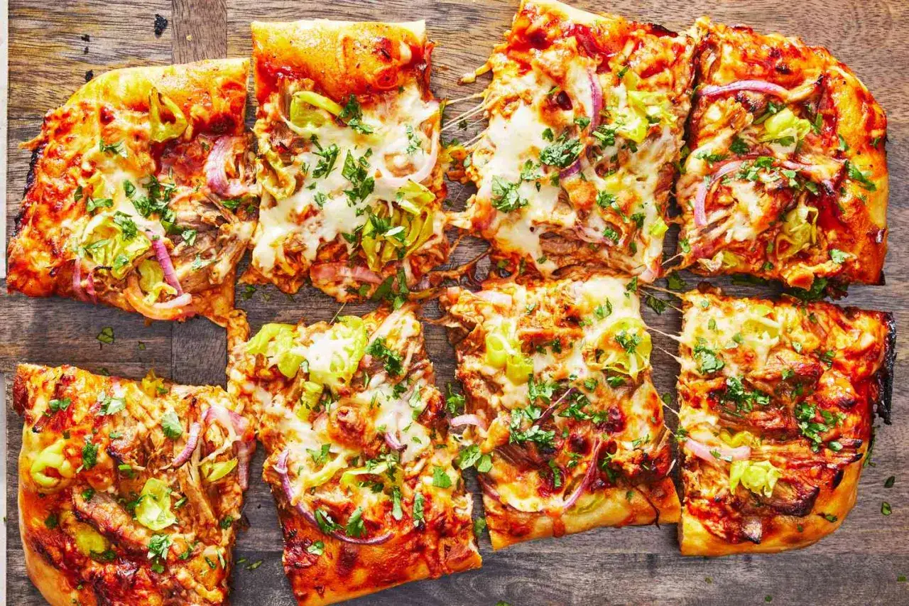 Verschiedene Pizza-Sorten mit geschmolzenem K&auml;se, pulled pork, Zwiebeln und Paprika, bestreut mit frischer Petersilie.