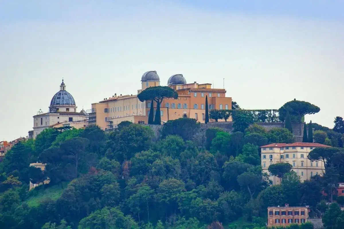 Letnia rezydencja papieska w Castel Gandolfo, z kopułą i obserwatoriami astronomicznymi, otoczona zielenią.