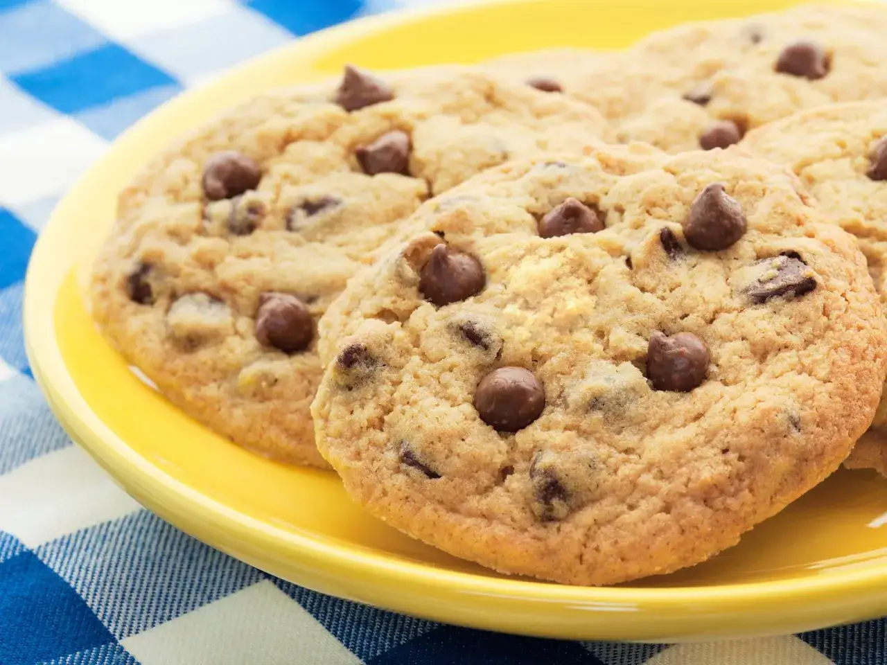 Saftige schoko cookies mit vielen Schokostückchen auf einem gelben Teller, bereit zum Genießen.