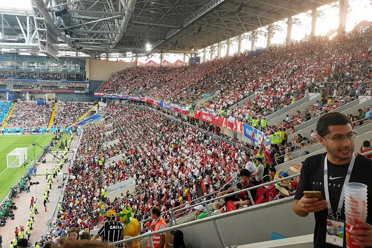 Tłum kibiców na moskiewskim stadionie, ubrani w czerwone i białe barwy, dopingują swoją drużynę.