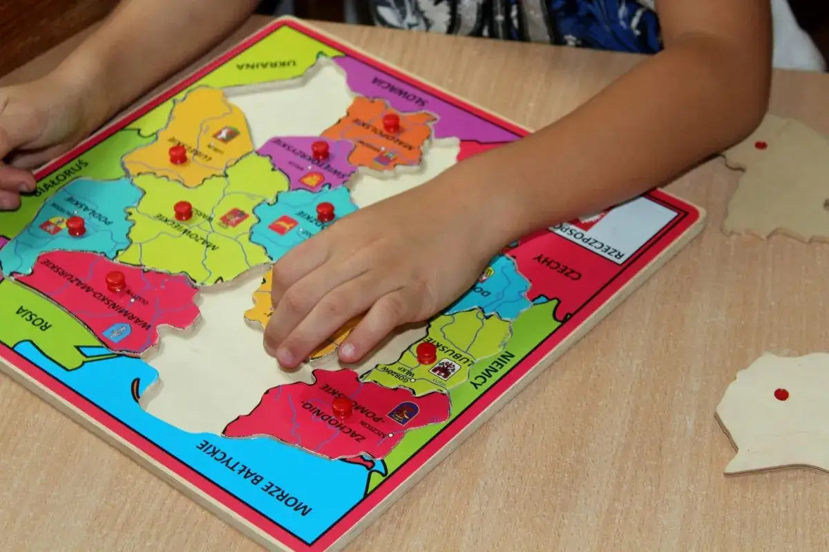 Dziecko układa puzzle z mapą Polski, ucząc się regionów. To świetne gry dydaktyczne w przedszkolu.