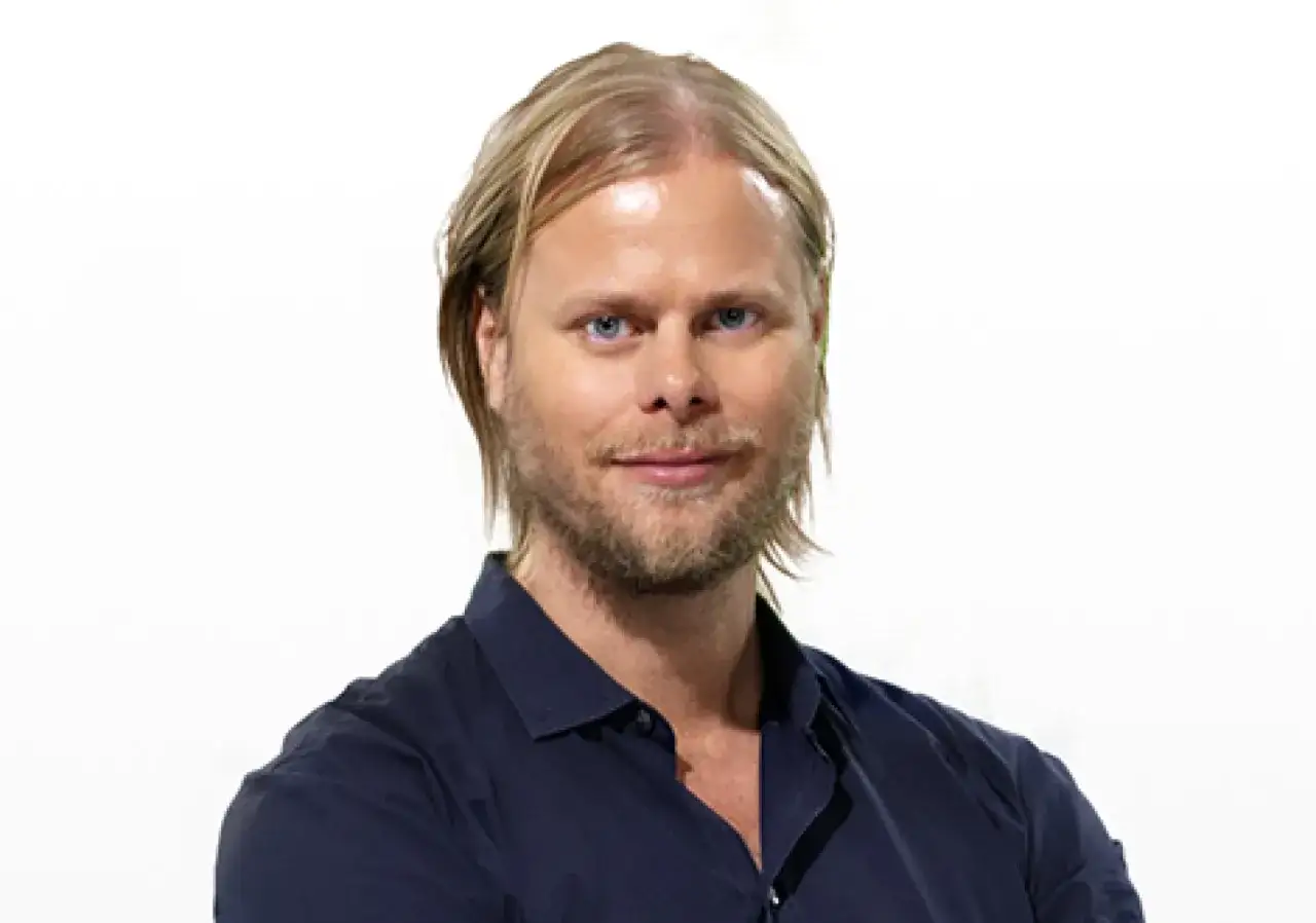 Per Nunstedt, en man med blont hår och blå ögon, ler mot kameran. Han bär en mörkblå skjorta.