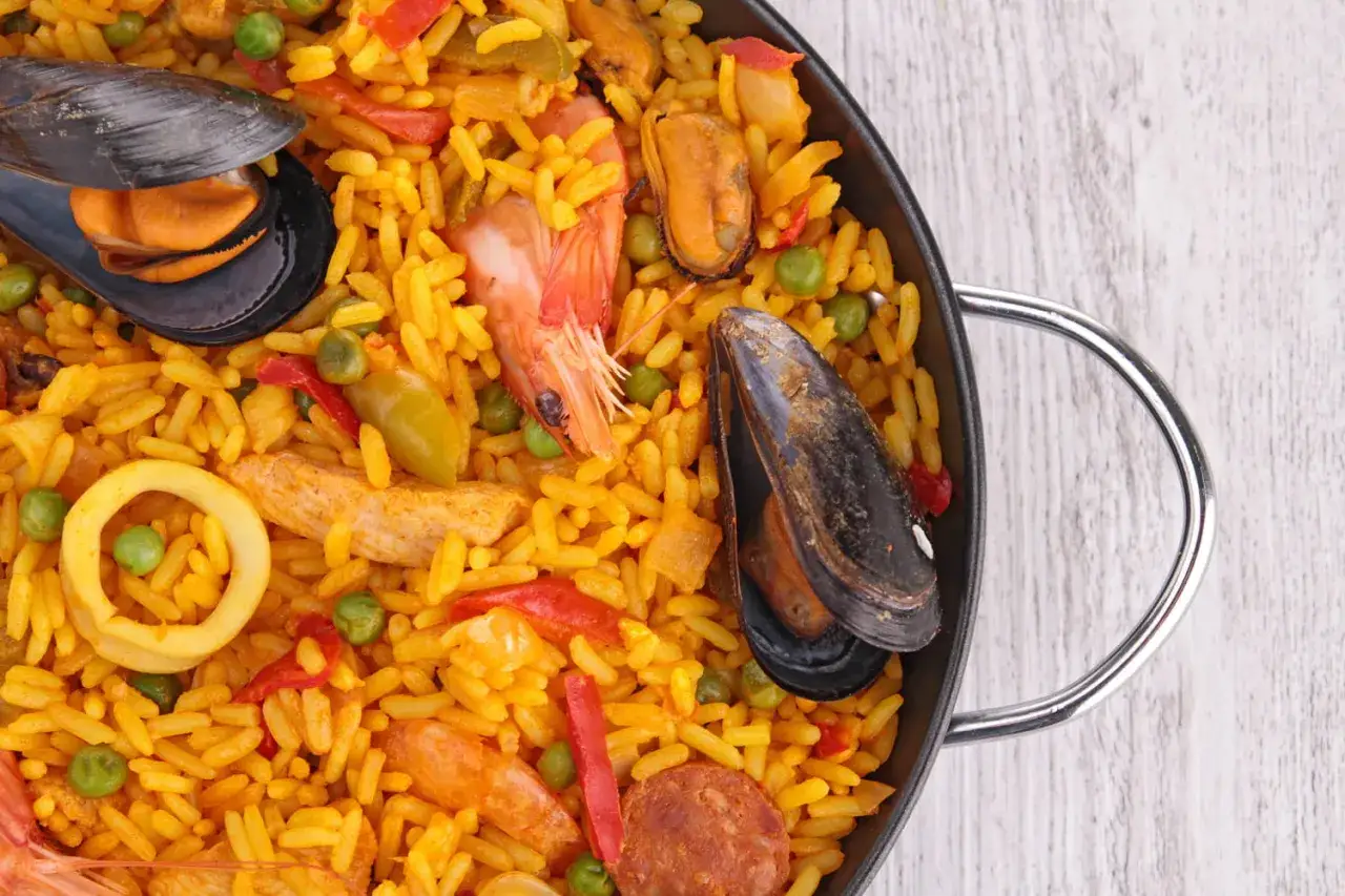 Un plat g&eacute;n&eacute;reux de paella royale, garni de moules, crevettes, calamars et chorizo, sur un lit de riz safran&eacute;.