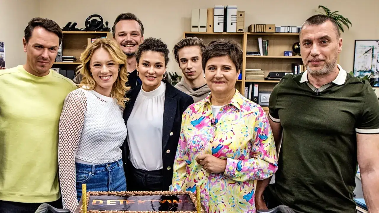 Uśmiechnięta detektywi obsada pozuje do zdjęcia z tortem.