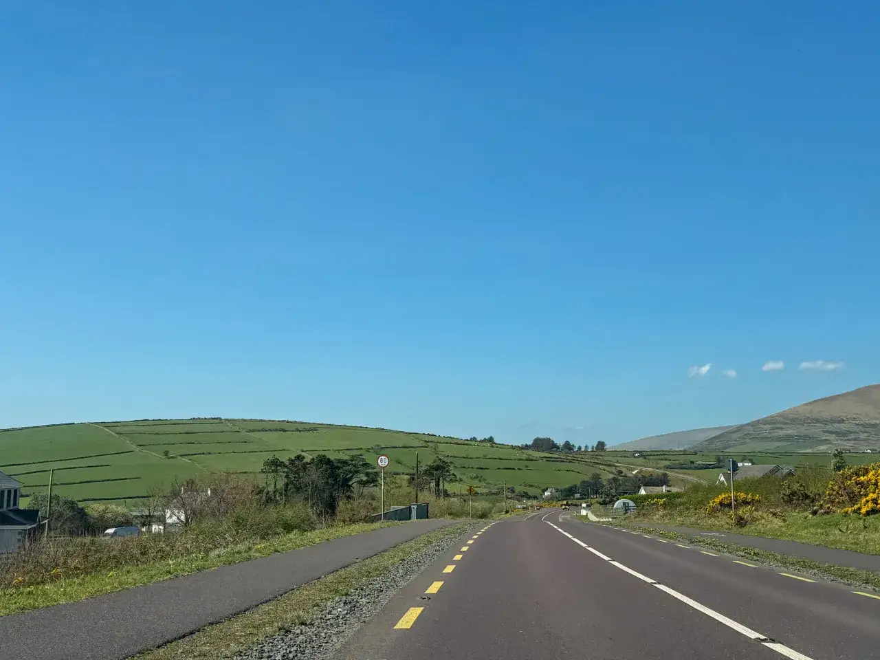 A scenic road winds through green Irish countryside, perfect for renting a car in Ireland and exploring.