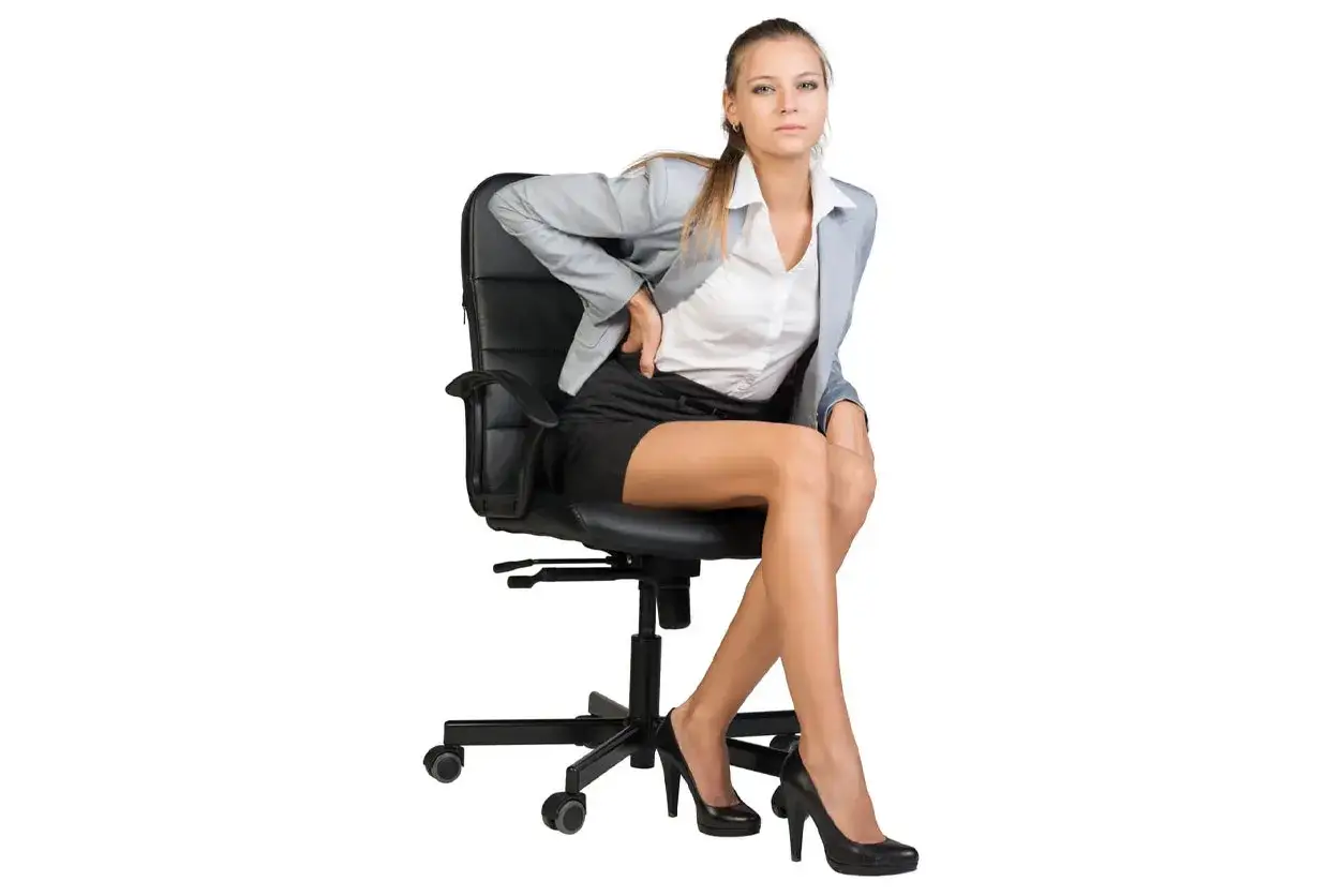 Femme d'affaires en tailleur, elle semble avoir mal au dos en rester assis sur sa chaise de bureau.