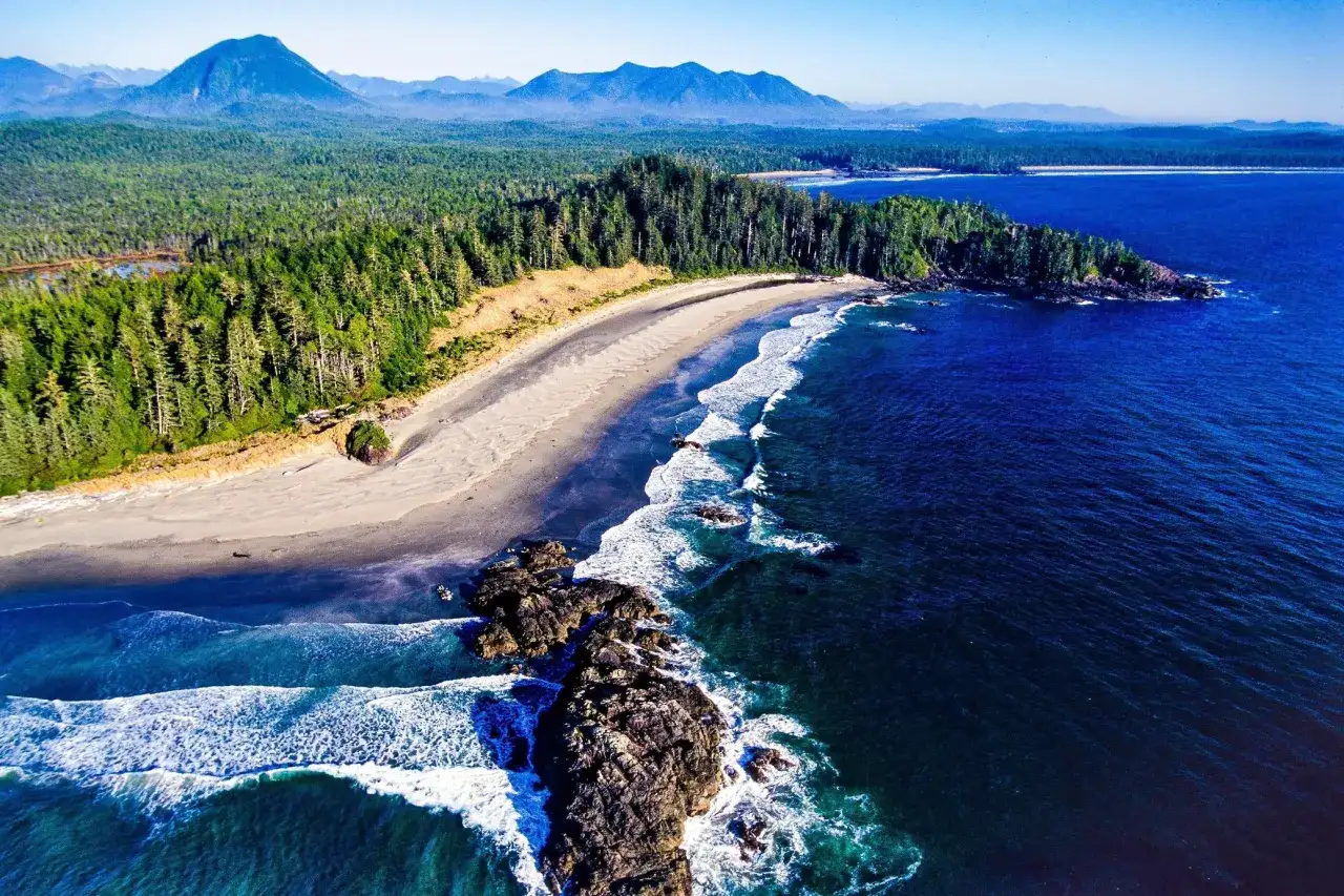 Traumhafte K&uuml;stenlandschaft auf Vancouver Island mit &uuml;ppigen W&auml;ldern, Sandstrand und dramatischen Felsen im t&uuml;rkisfarbenen Meer.