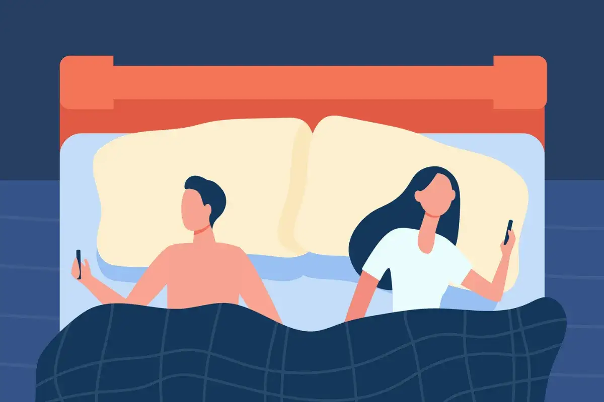 Couple dans un lit, chacun sur son téléphone. Leurs regards sont détournés, une illustration de la distance qui peut naître, et du désir de connexion,